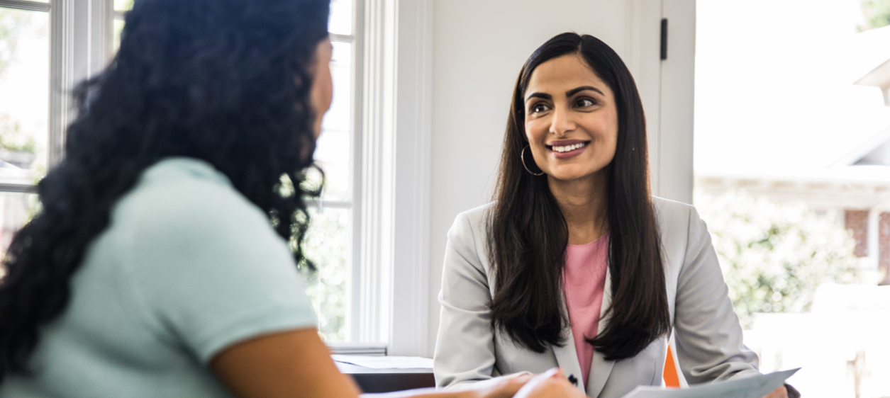 Two female employees looking at laptop while solving a business challenge