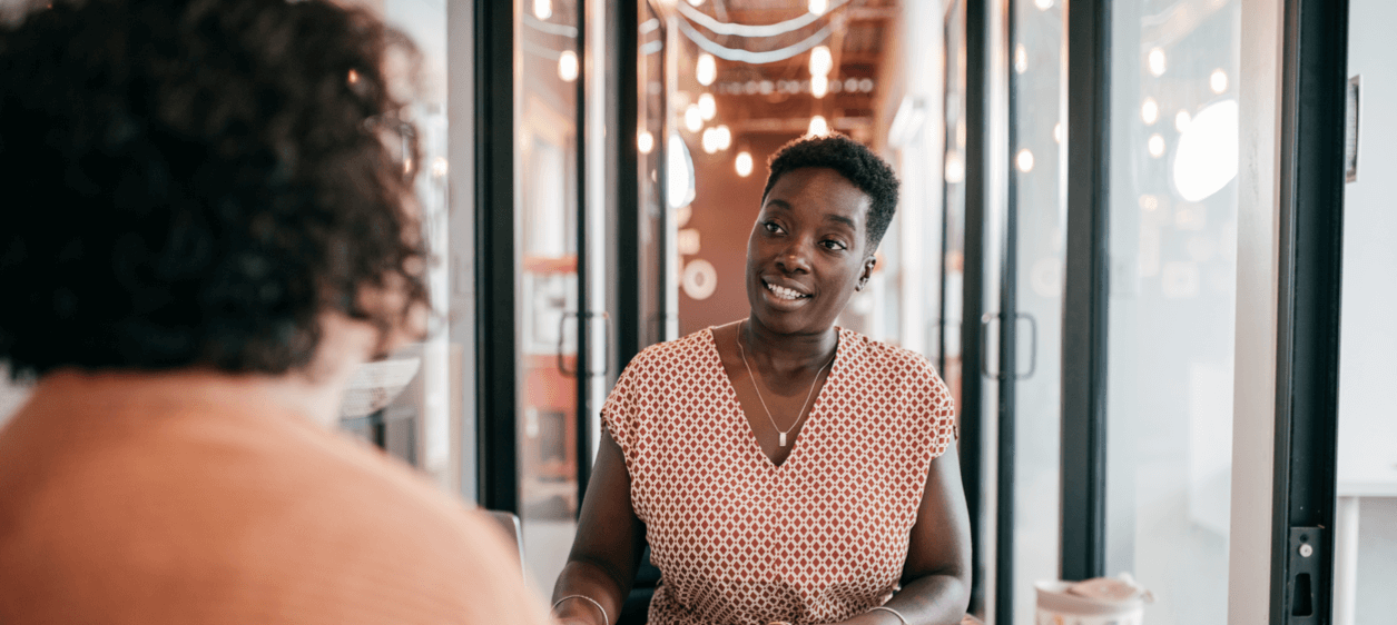 Two female employees looking at laptop while solving a business challenge